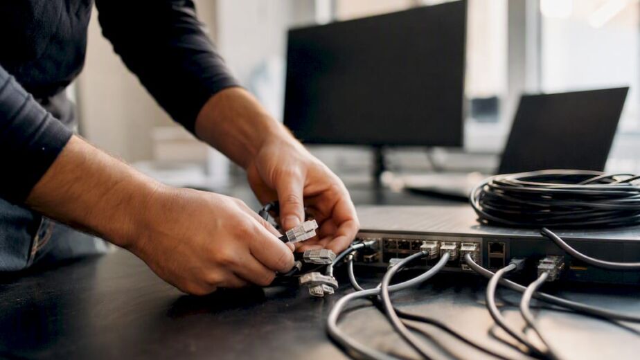 Hände beim Verdrahten von Datenanschlüssen auf dem Schreibtisch